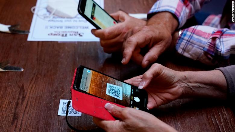 Janie Andrich and Craig Andrich use their phones to look up a digital menu via a QR code on the table in San Pedro Brewing Company on Friday, May 29, 2020, in the San Pedro area of Los Angeles. Restaurants were allowed to open their dining rooms with restrictions today. (AP Photo/Ashley Landis)